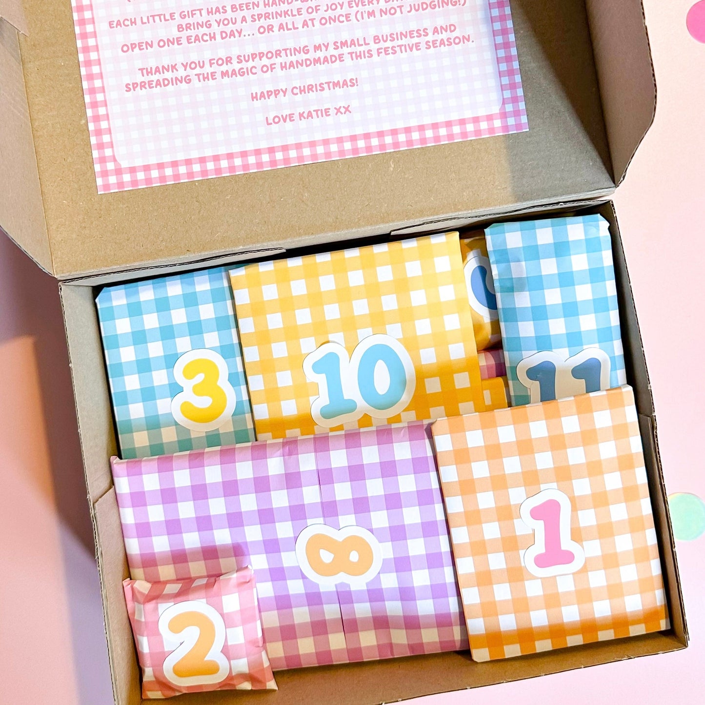 Box of colorful wrapped presents with numbers on a pink background