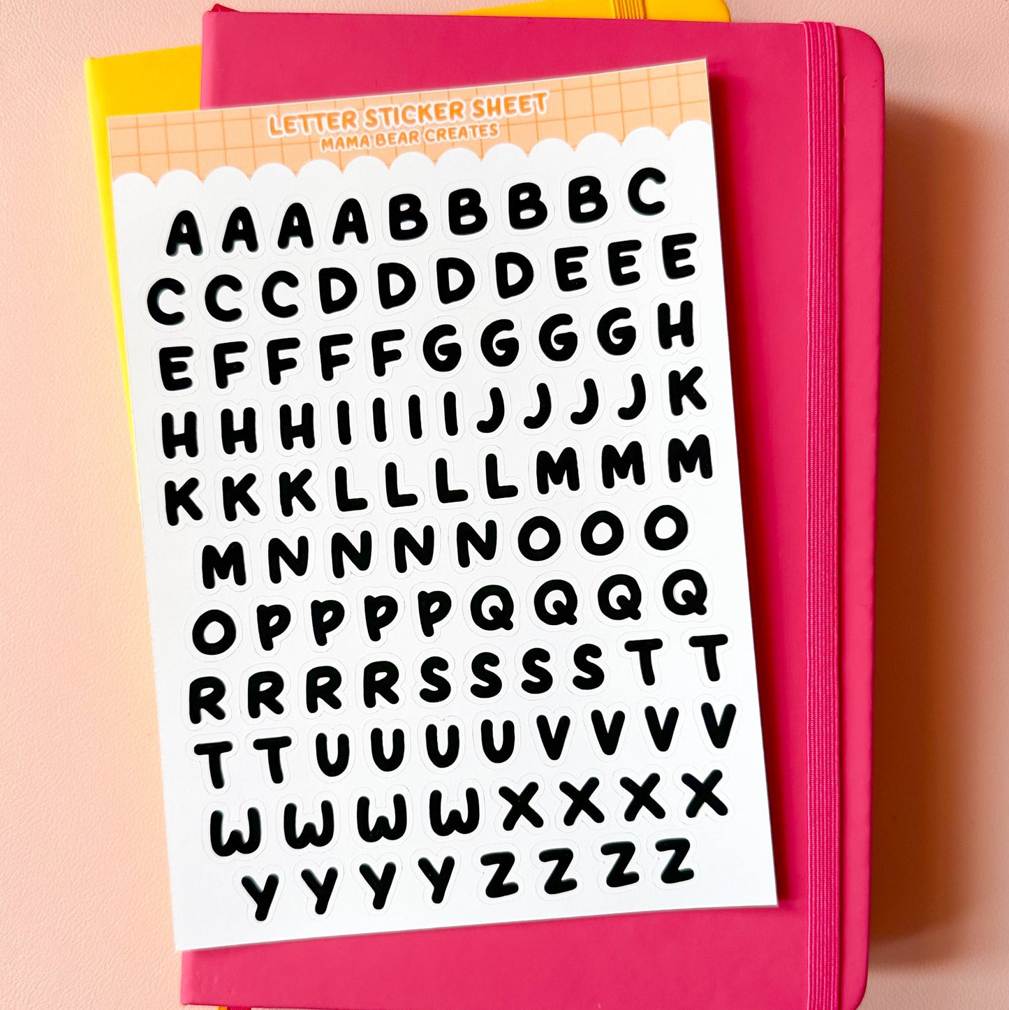 Pink notebook with letter stickers on a pink background