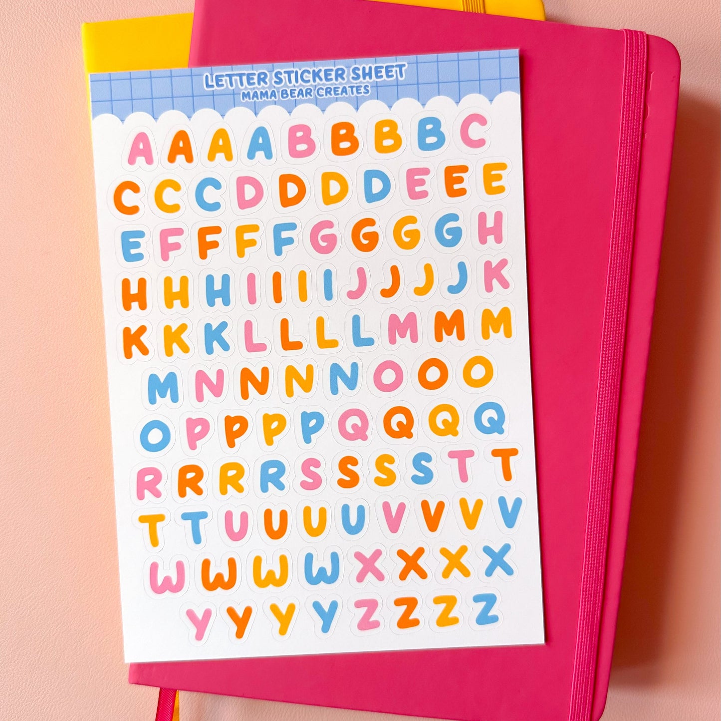 Pink notebook with colorful letter stickers on a peach background