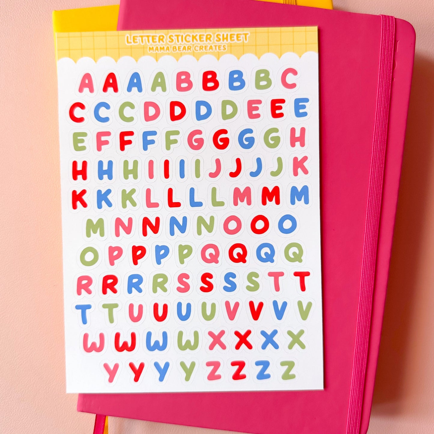 Pink notebook with colorful letter stickers on a pink background