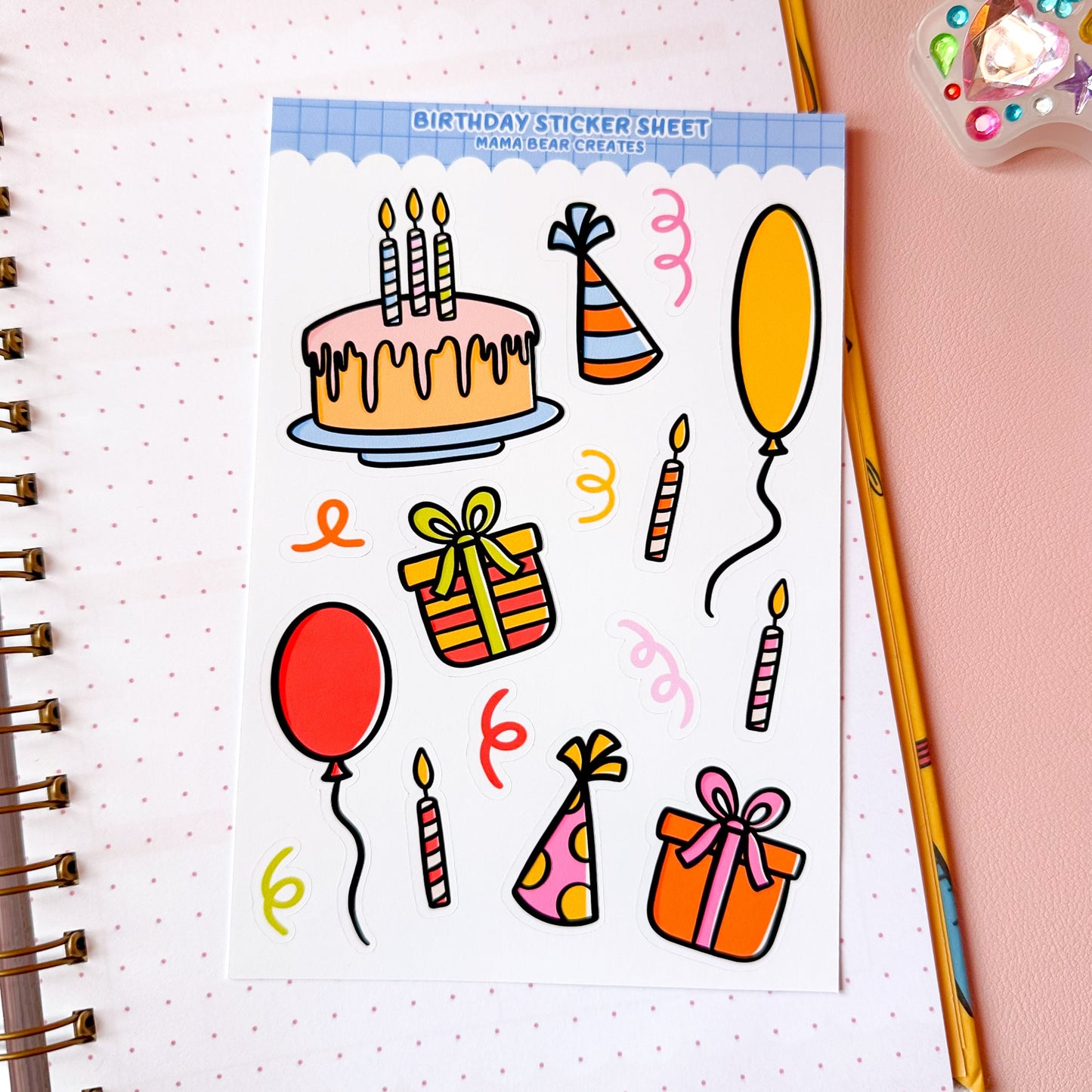 Sheet of birthday-themed stickers with a cake, balloons, and presents on a notebook page.