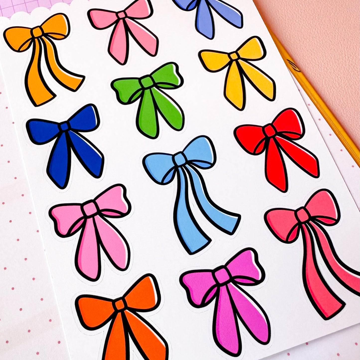 Sheet of colorful bow stickers on a pink polka dot background