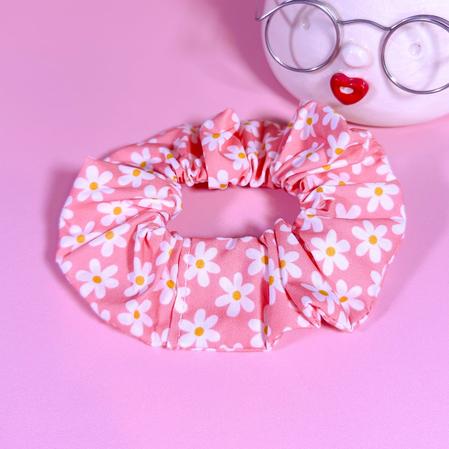 Pink scrunchie with white floral pattern on a pink background
