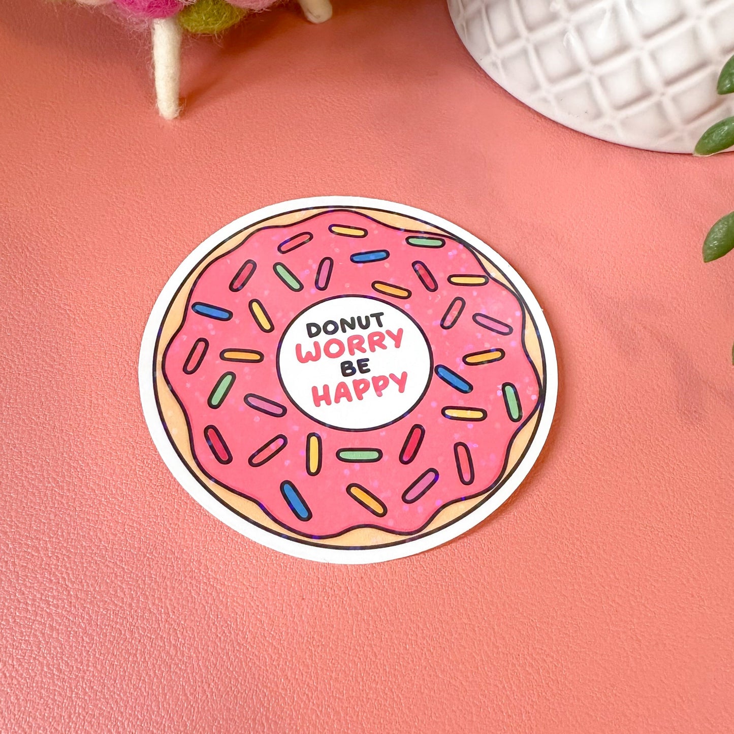Sticker with a pink donut design and text on a pink surface