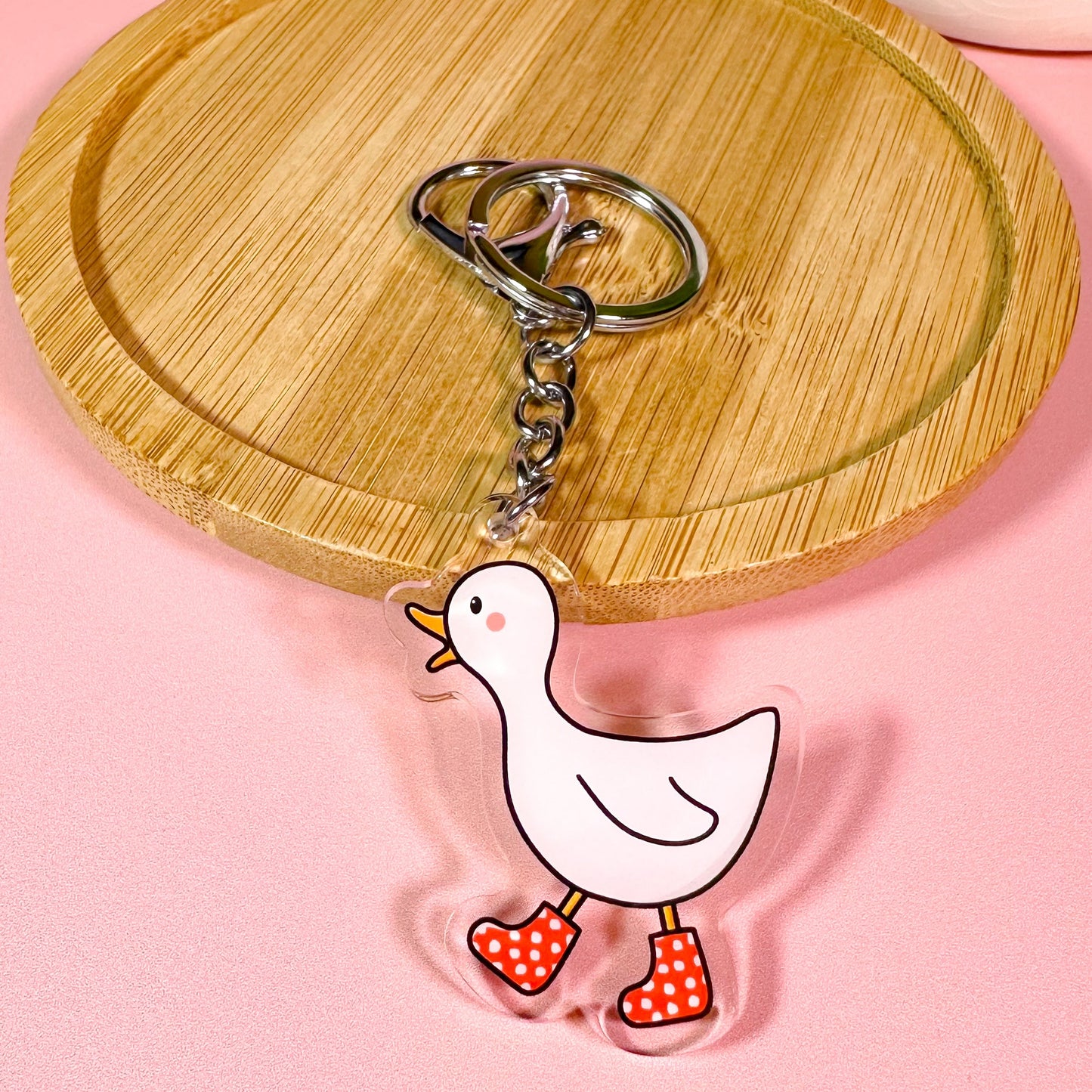 Keychain with a cartoon duck design on a pink background