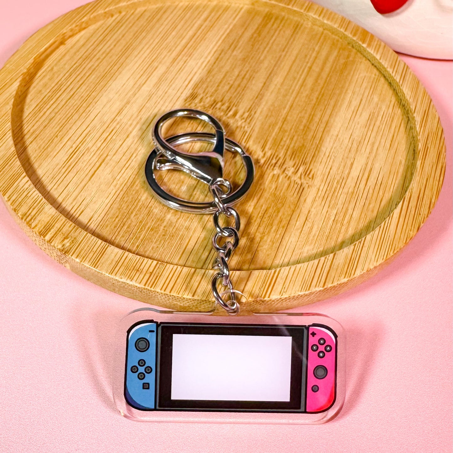 Keychain on a small electronic device with a wooden board and pink background