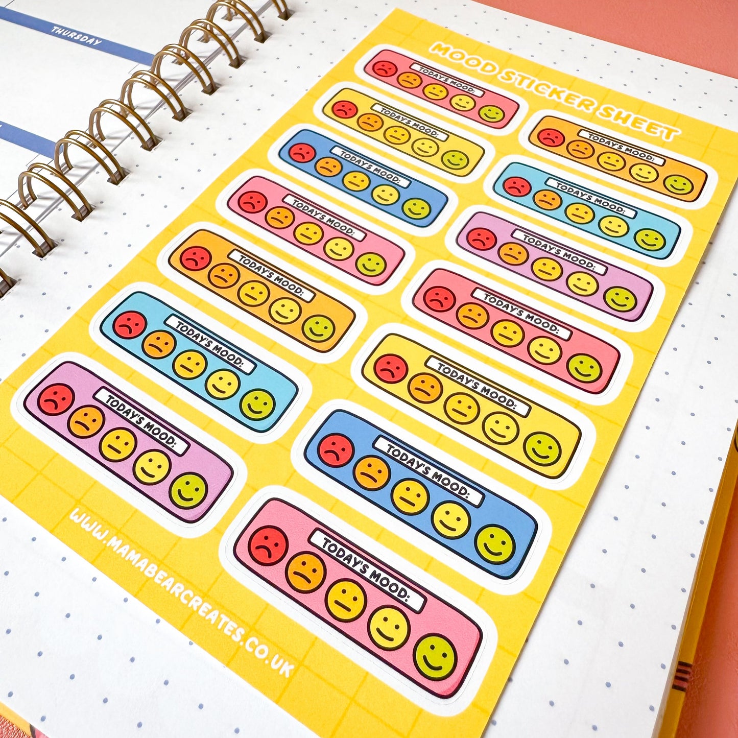 Colorful emoji-themed stickers on a planner page with a pink background