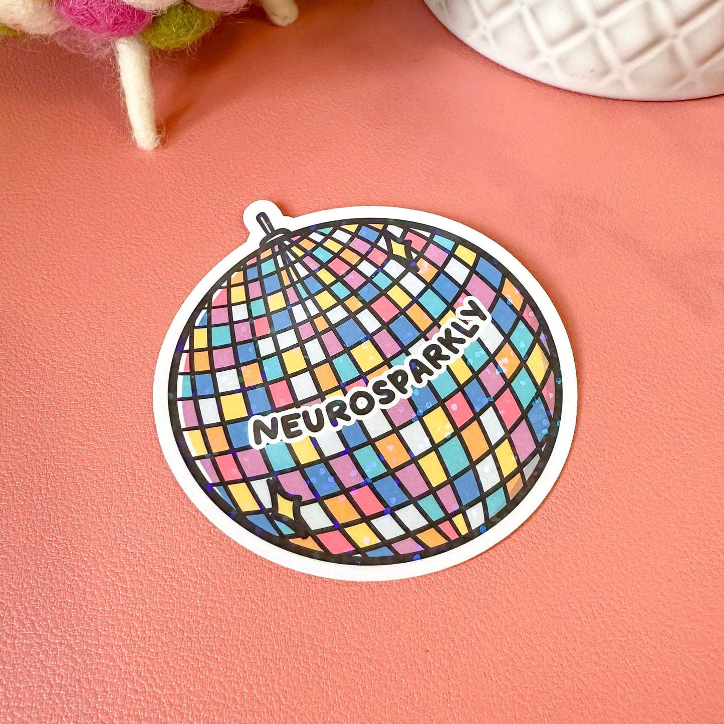 Colorful sticker with 'Neurospark' text on a pink surface