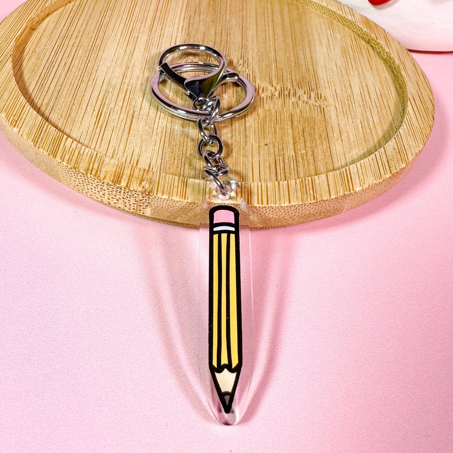 Keychain shaped like a pencil on a pink background