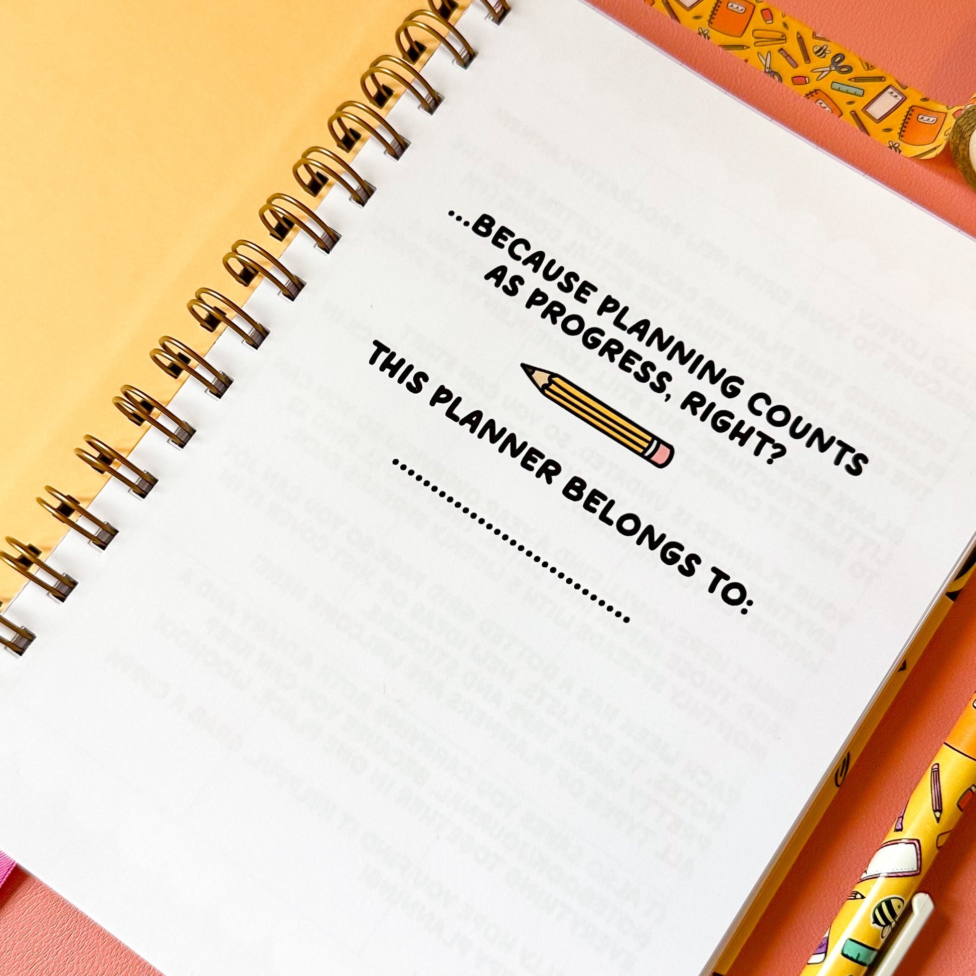 Spiral-bound planner with a quote and a pen on a colorful background