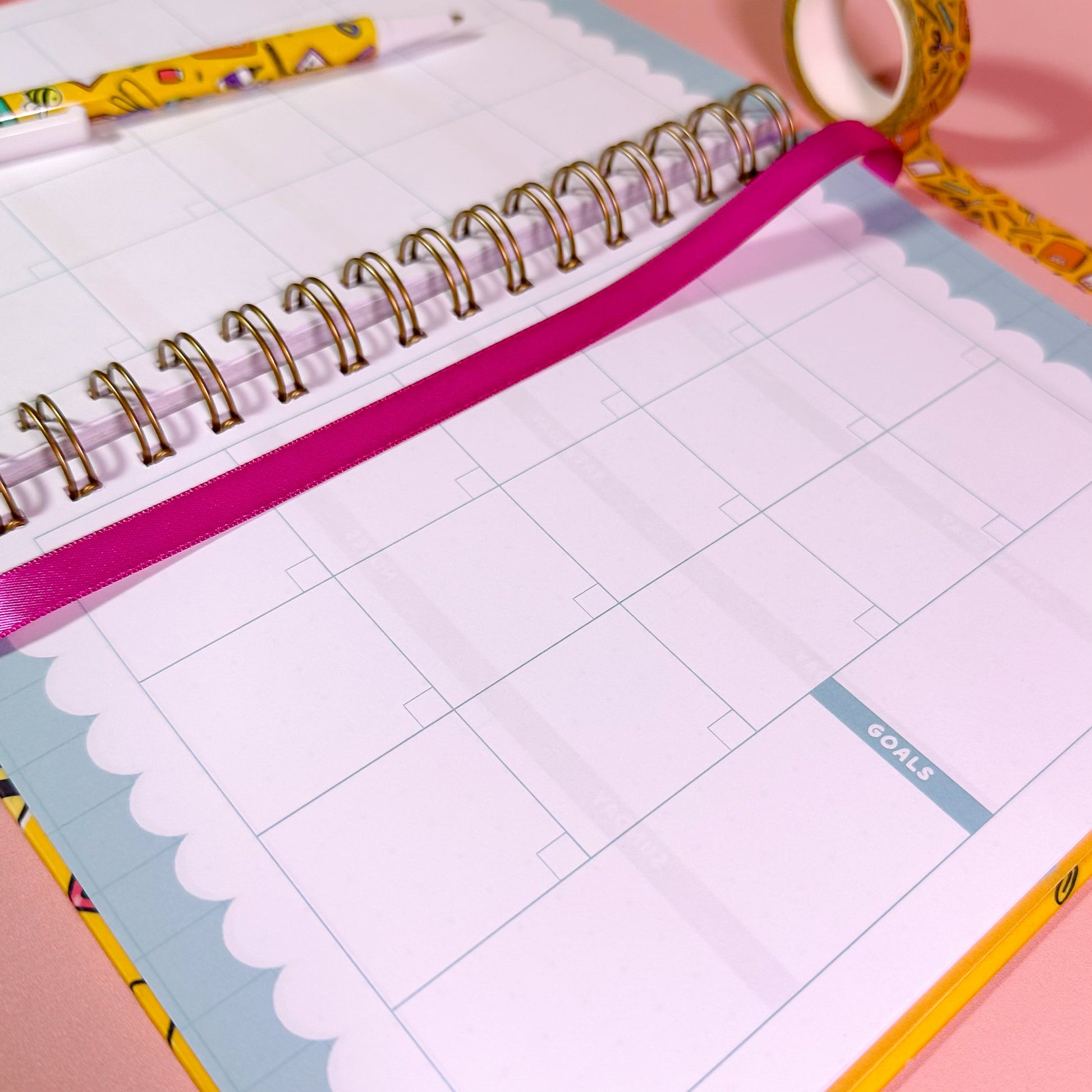 Open planner with grid pages on a pink background