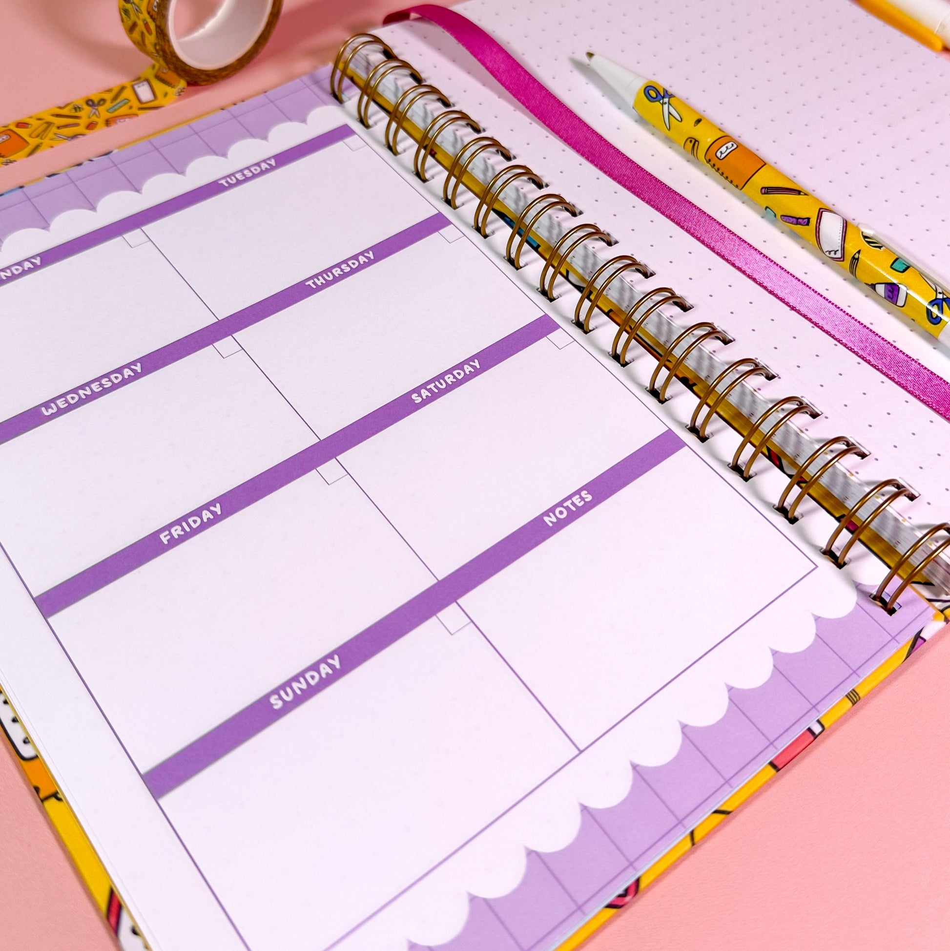 Weekly planner with colorful pen and washi tape on a pink background