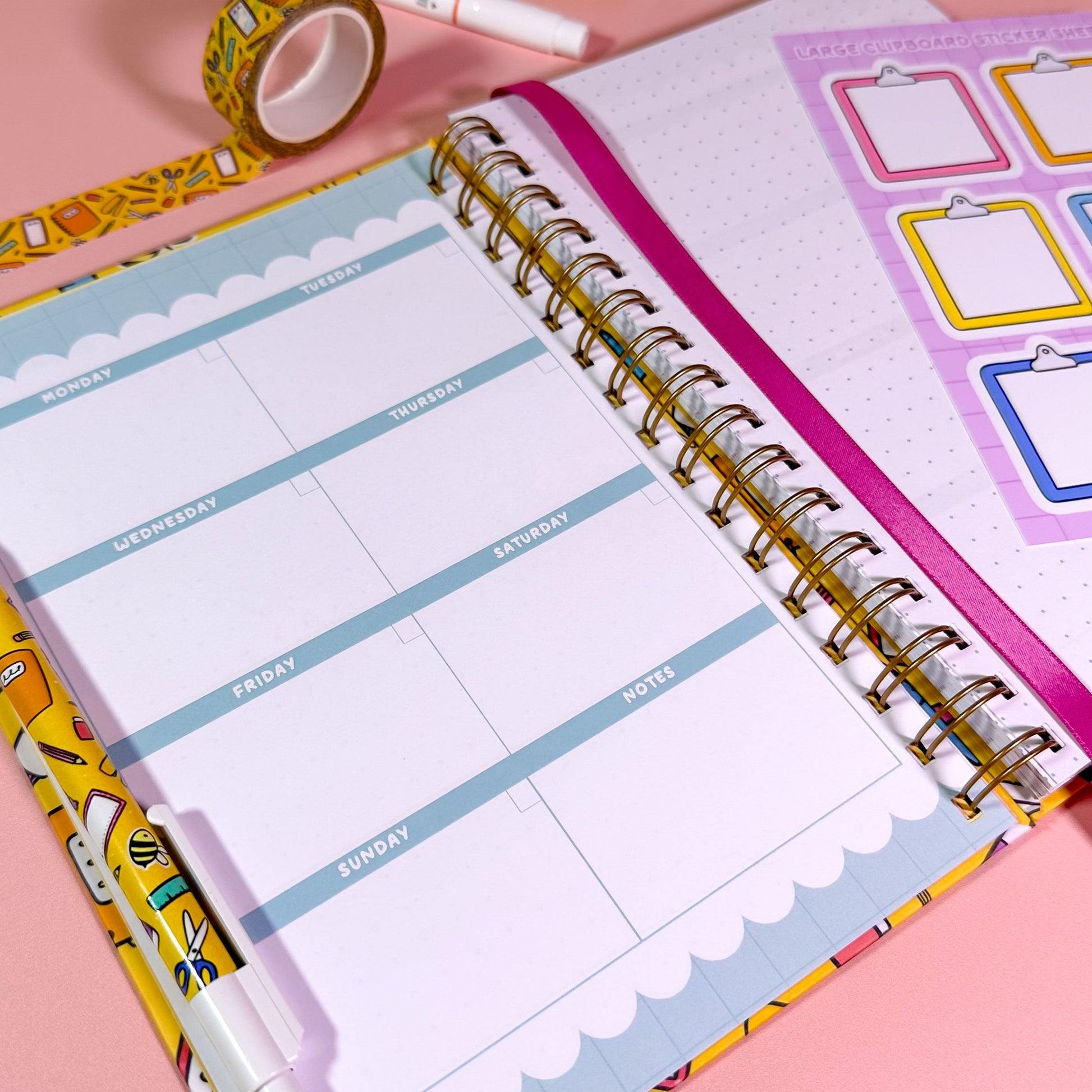 Open planner with weekly layout on a pink background