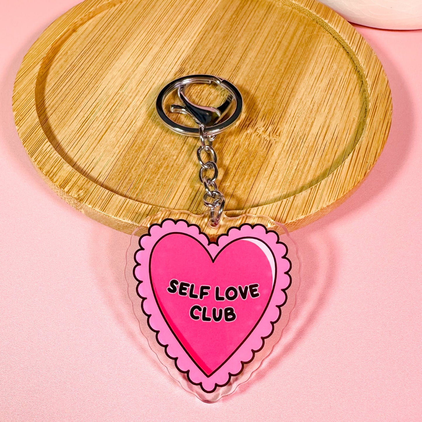 Heart-shaped keychain with 'Self Love Club' text on a pink background