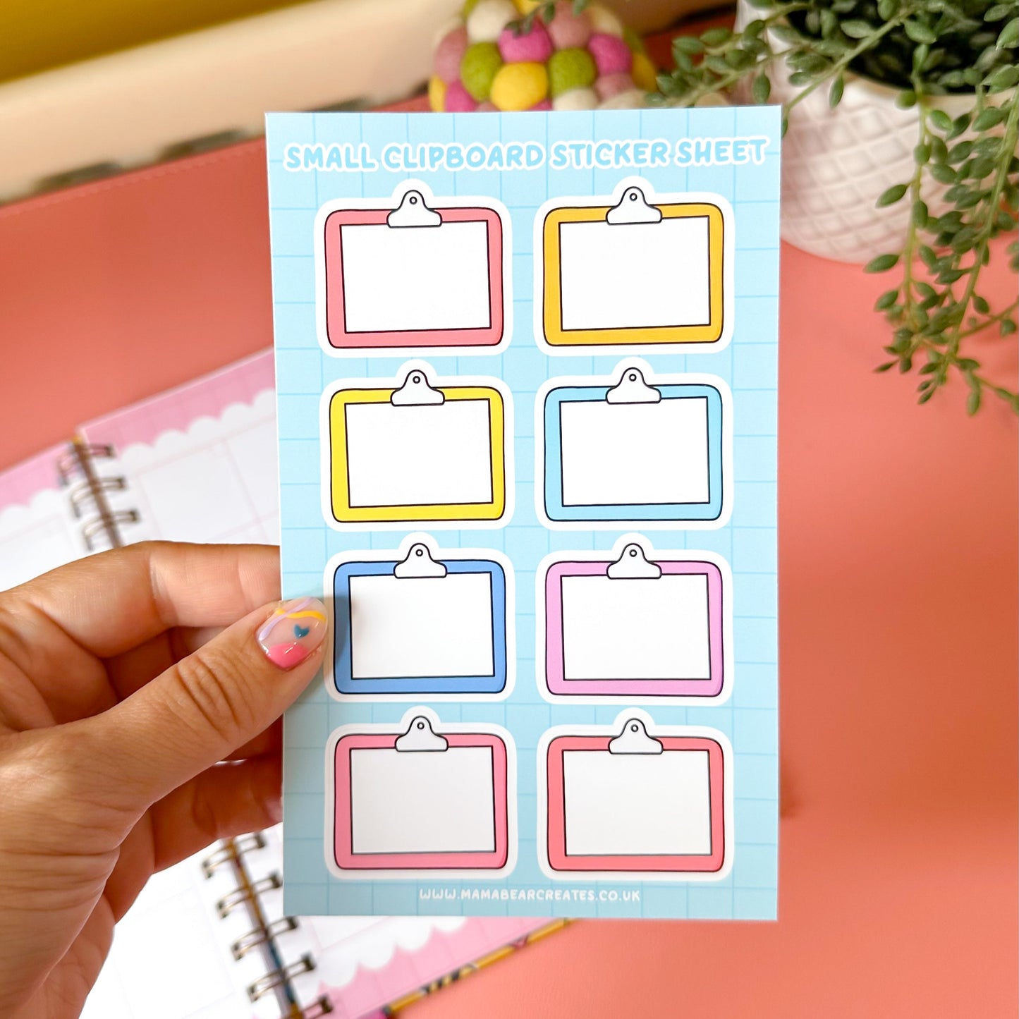Sheet of small clipboard stickers held by a hand with a colorful background