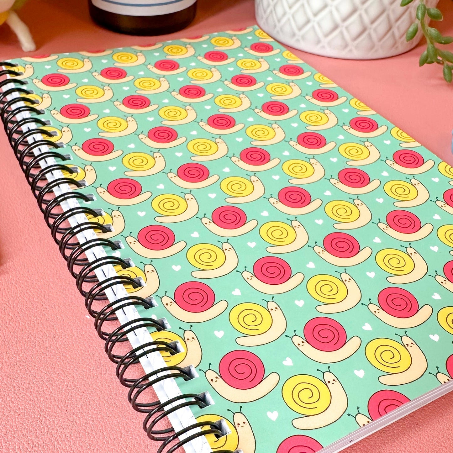 Notebook with snail pattern on a pink surface