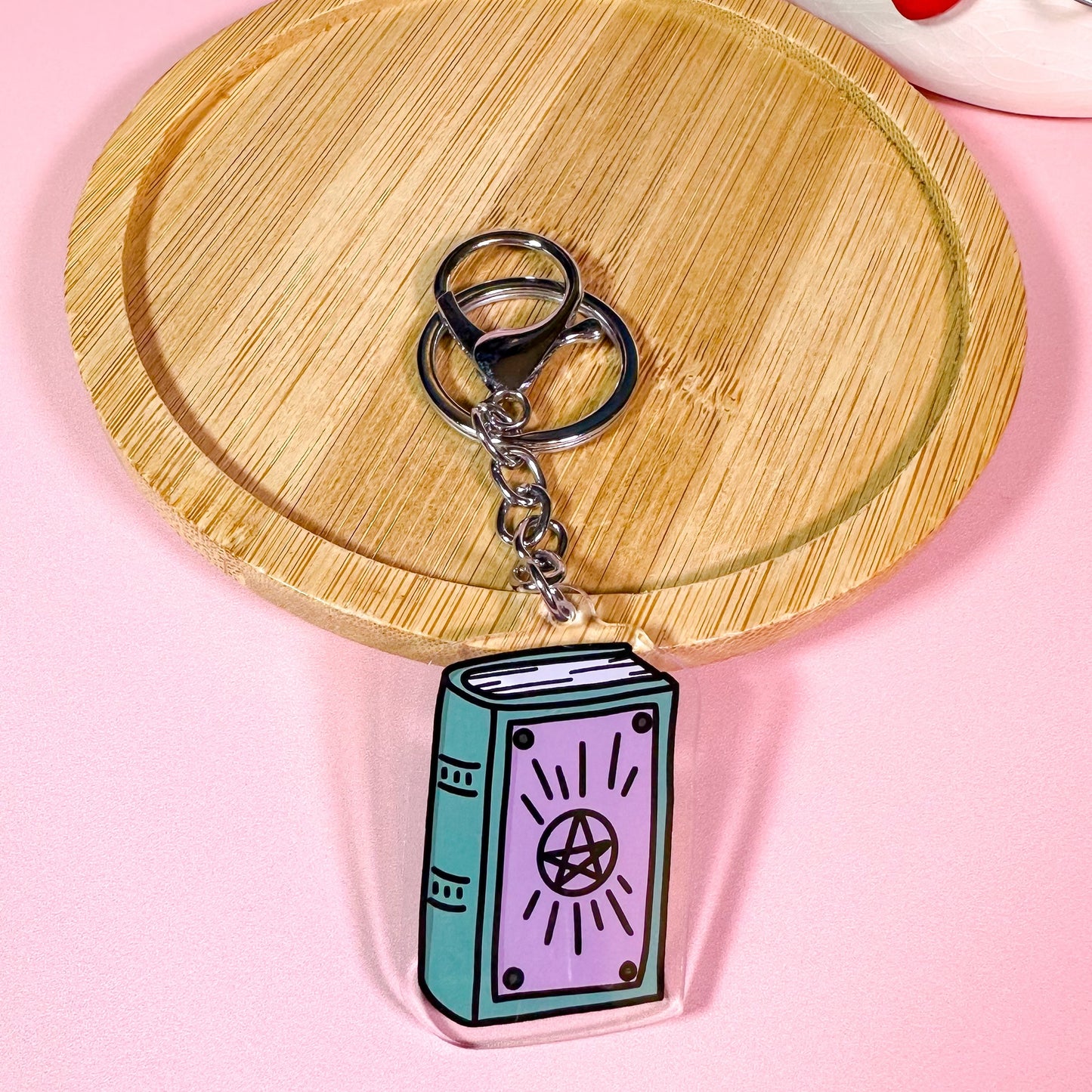 Keychain shaped like a book with a pentagram on a wooden coaster with a pink background