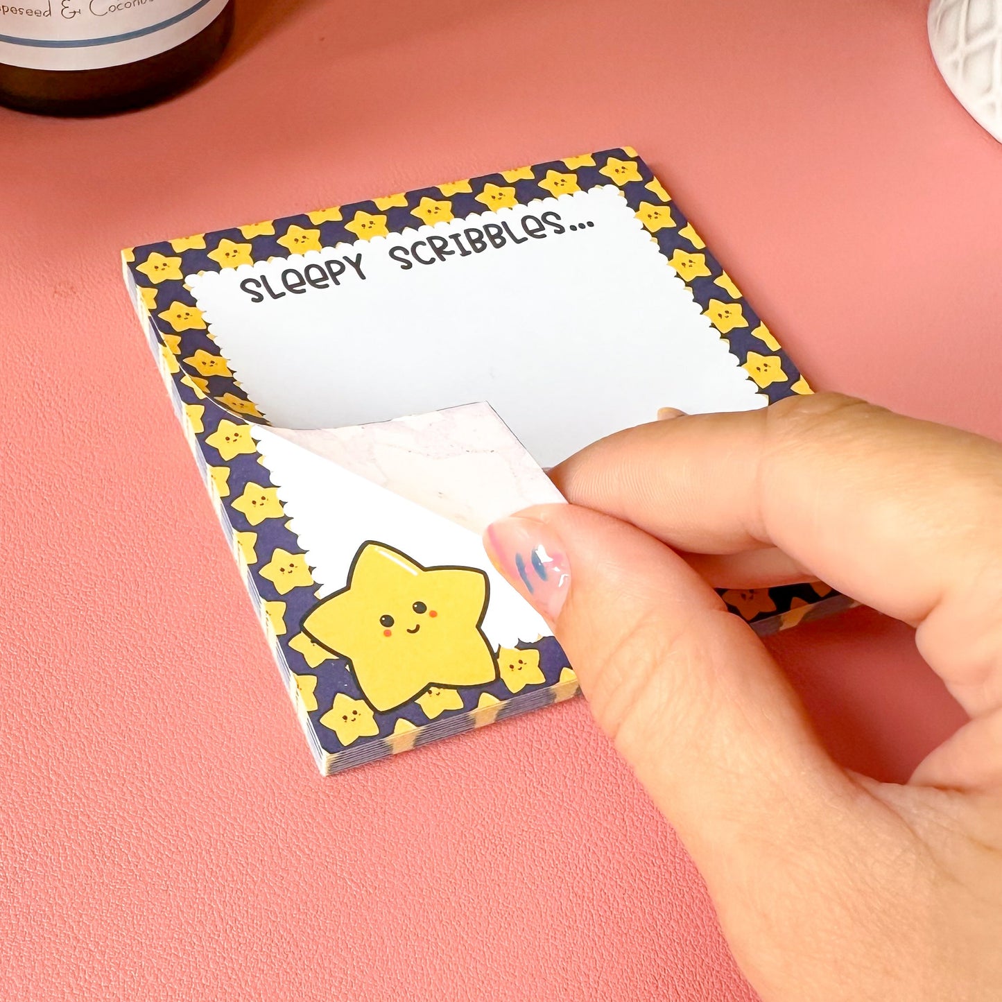 Small notepad with star design and 'Sloppy Scribbles' text on a pink surface.