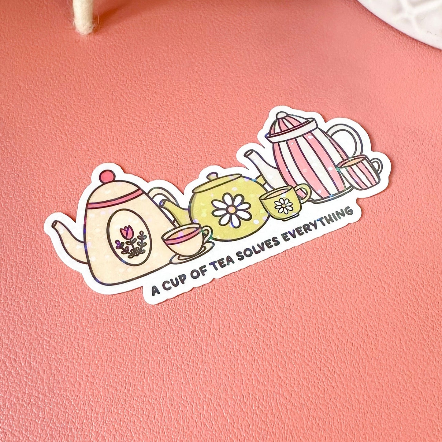 Sticker with teapots and text on a pink surface