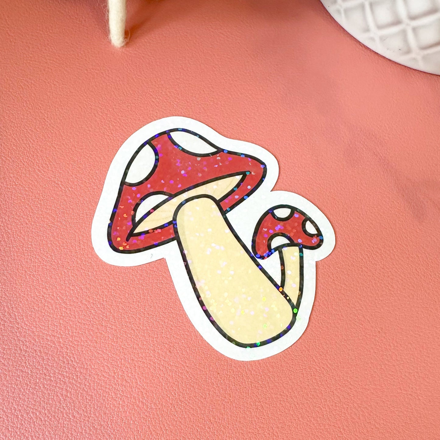 Colorful mushroom sticker on a pink surface with decorative items in the background
