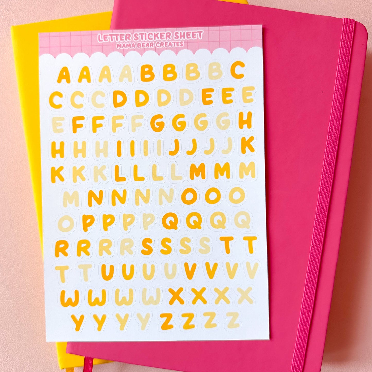 Sheet of yellow letter stickers on a pink notebook with a pink background