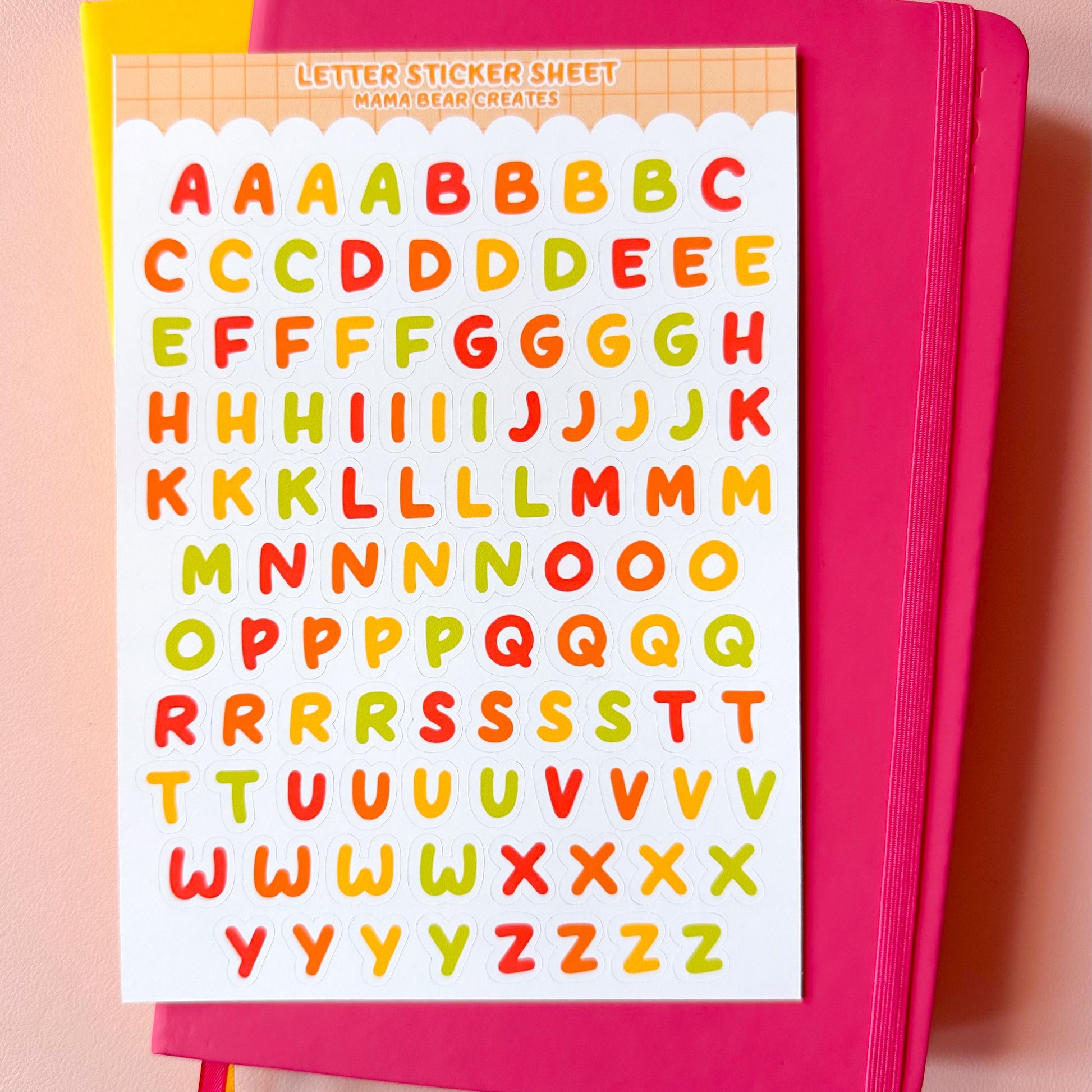 Pink notebook with colorful alphabet stickers on a pink background