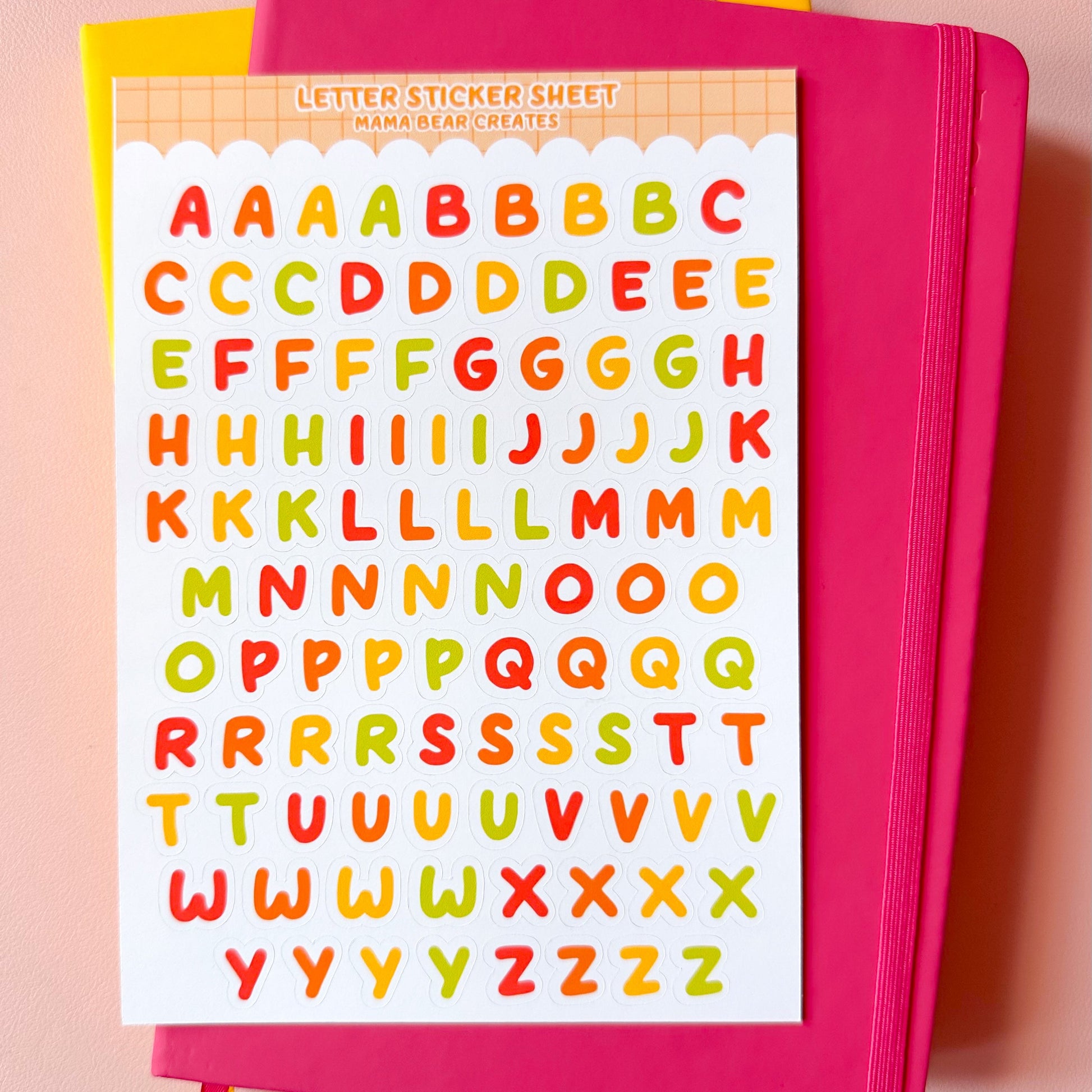 Pink notebook with colorful alphabet stickers on a pink background