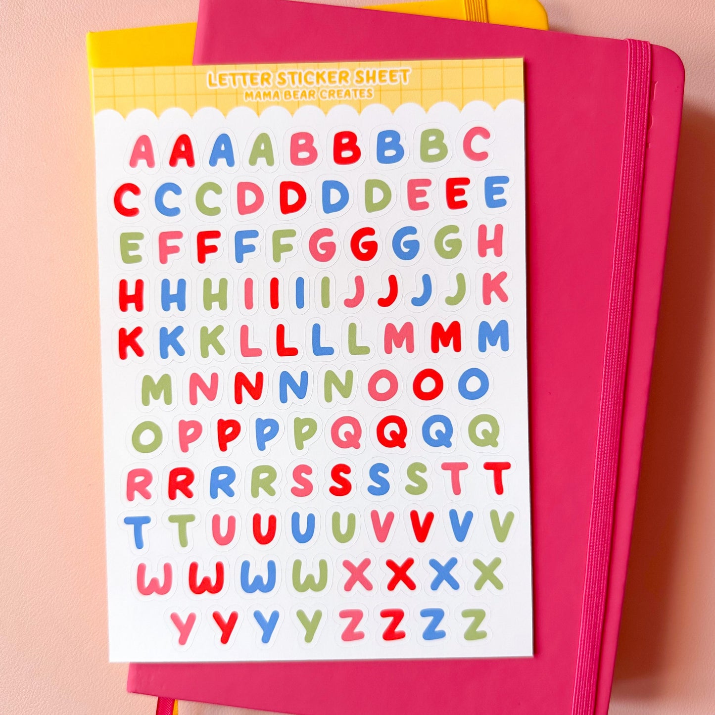 Pink notebook with colorful letter stickers on a pink background