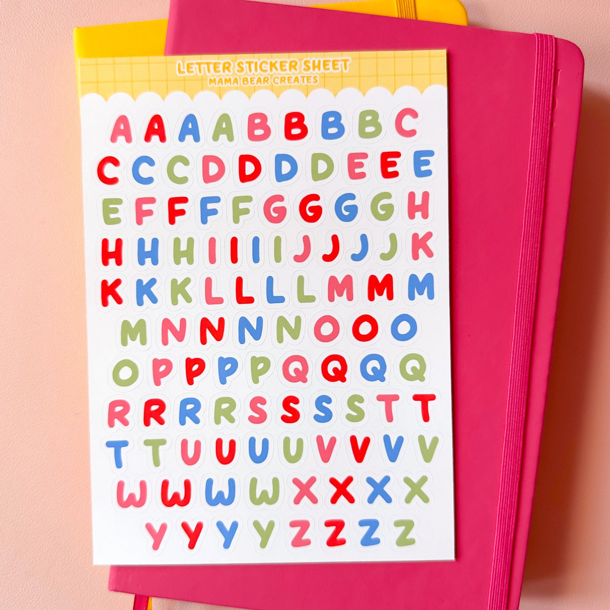 Pink notebook with colorful letter stickers on a pink background