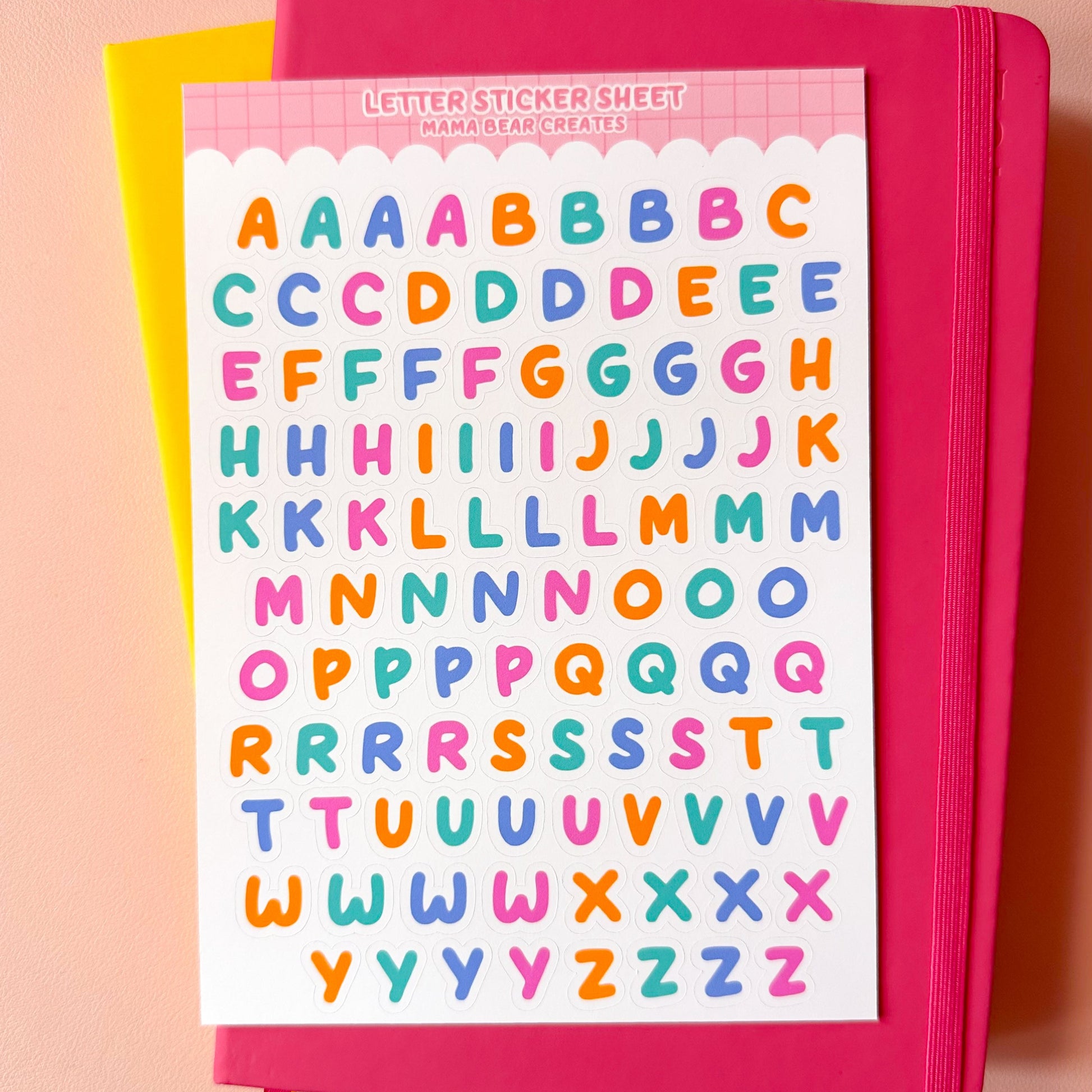 Pink notebook with colorful letter stickers on a pink background