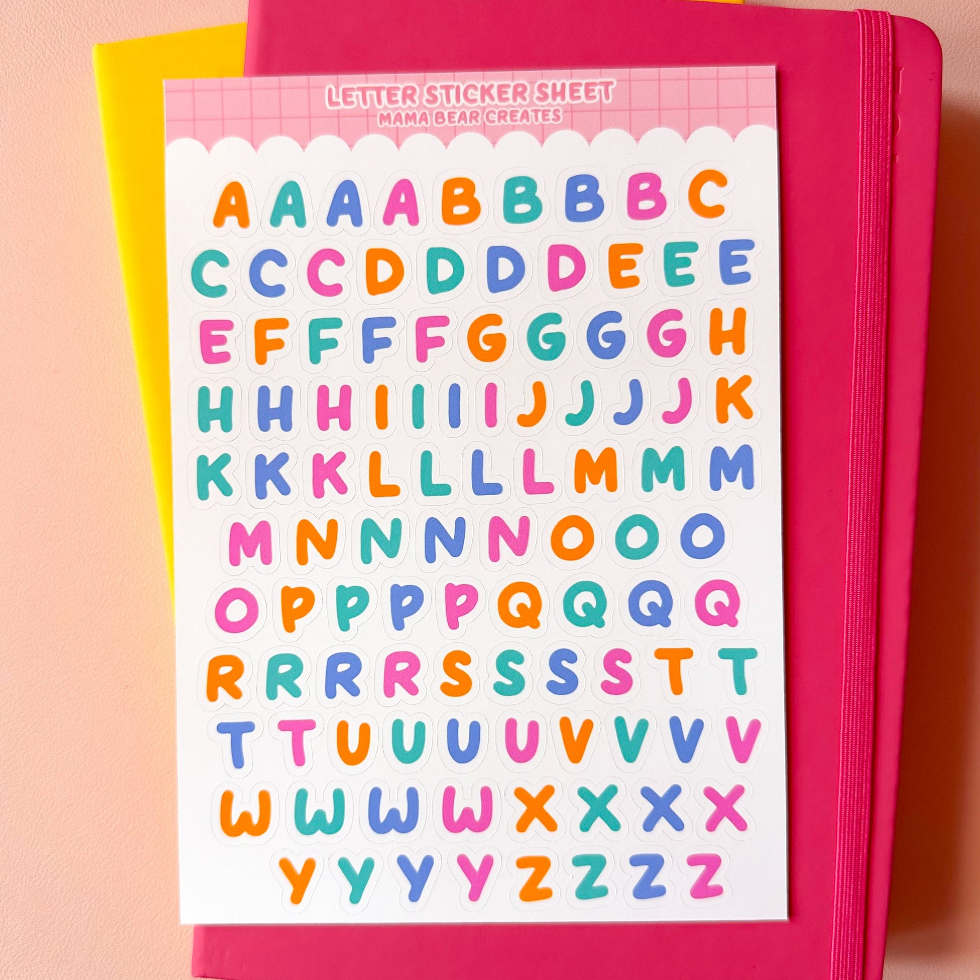 Pink notebook with colorful letter stickers on a pink background