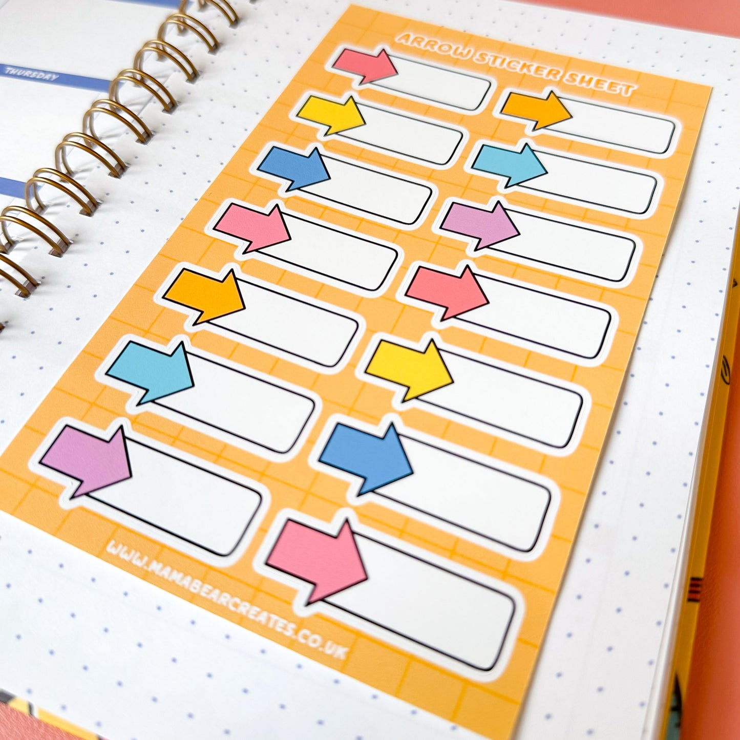 Sheet of colorful arrow stickers on a spiral-bound notebook with a pen.