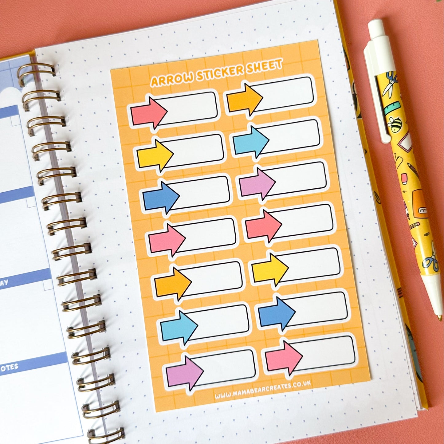 Sticker sheet with colorful arrows on a planner page with a pen and plant in the background.