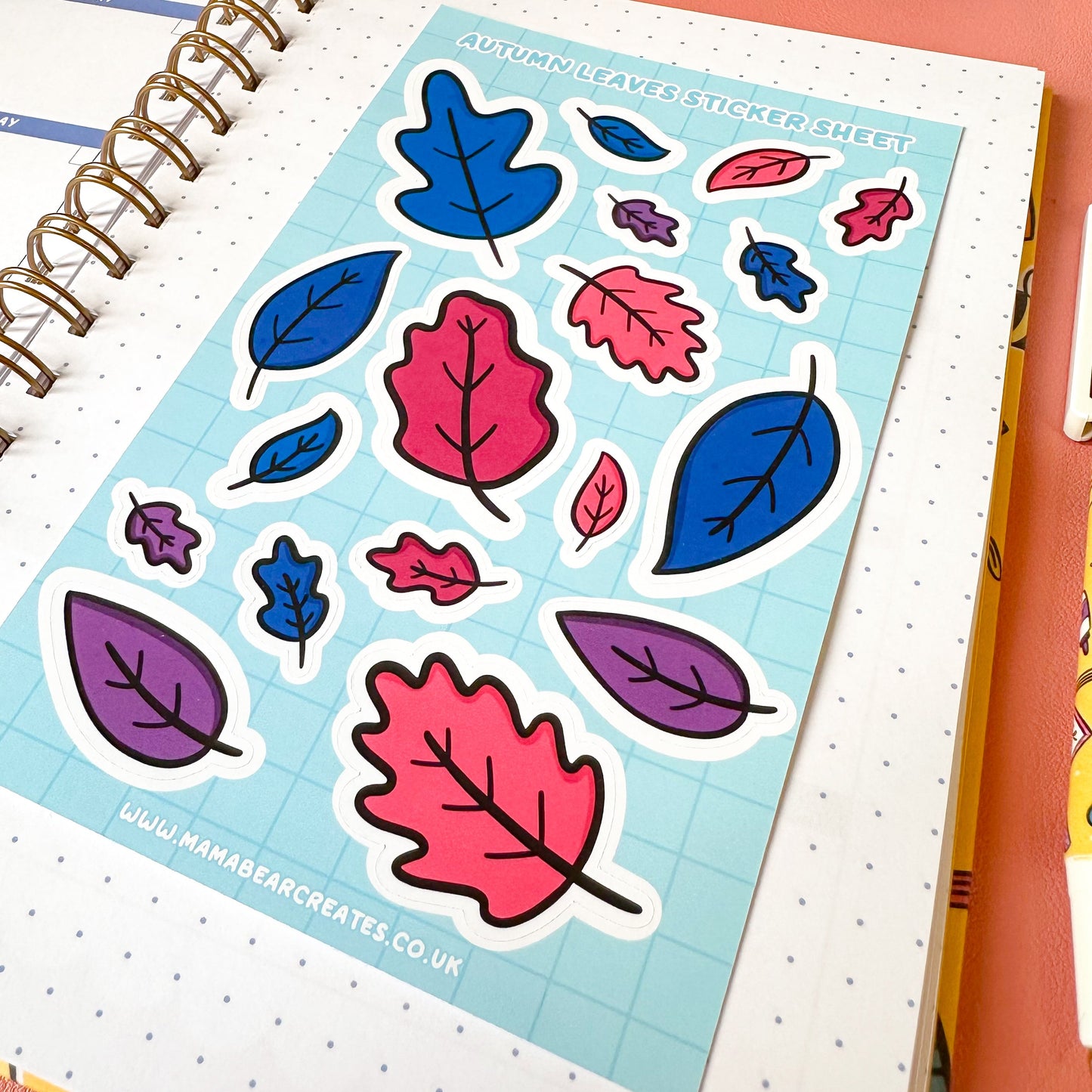 Sheet of colorful leaf stickers on a notebook with a pink background