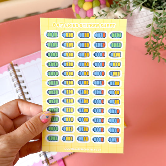 Sheet of colorful stickers held by a hand with a pink background