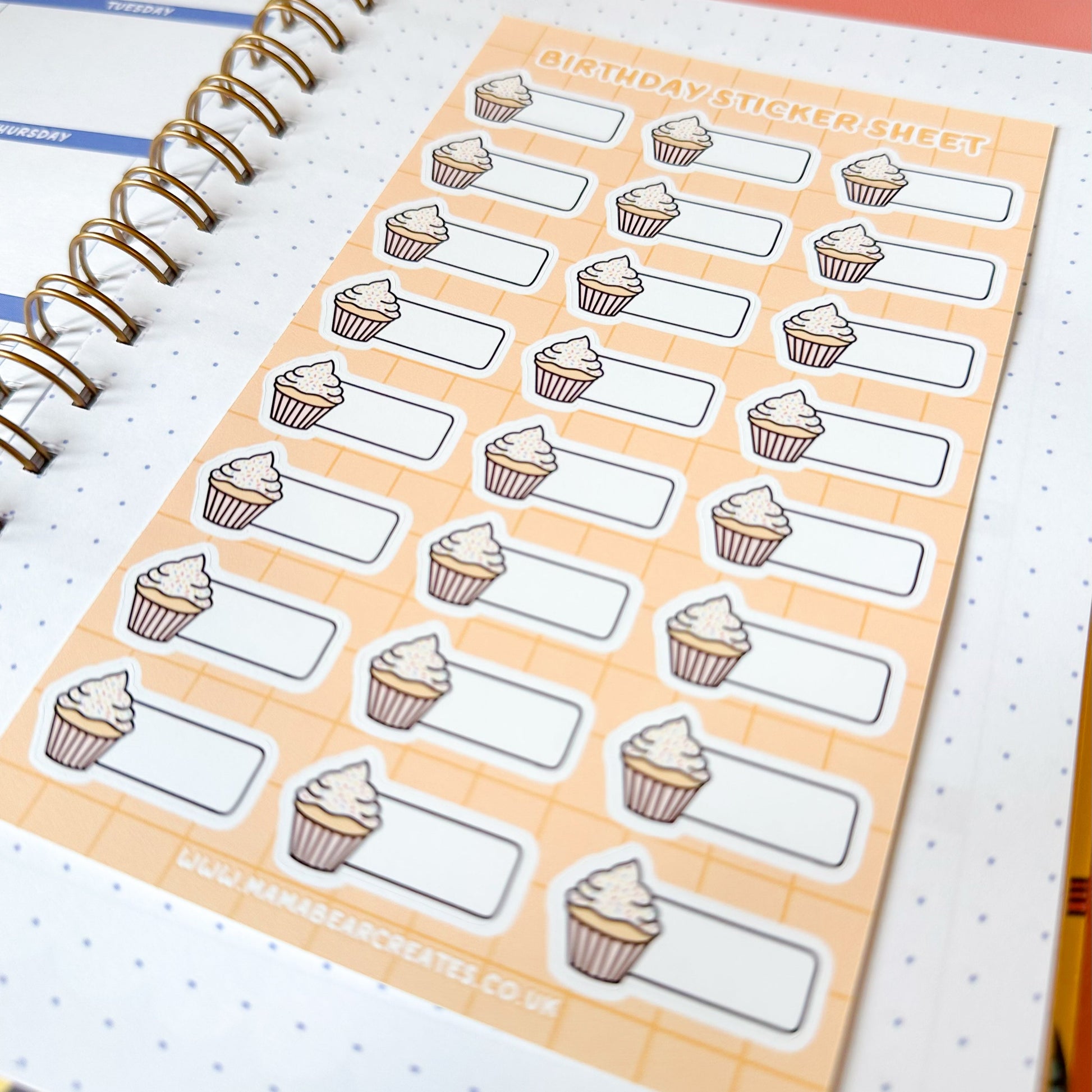 Sheet of cupcake-themed stickers on a planner with a pink cover.