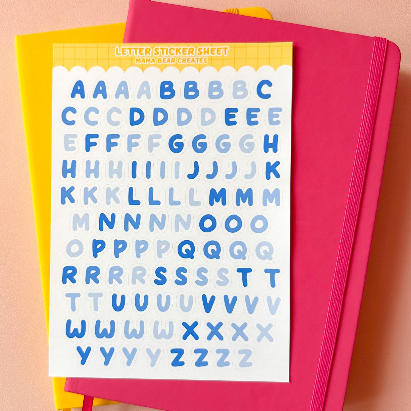 Pink notebook with letter stickers on a peach background