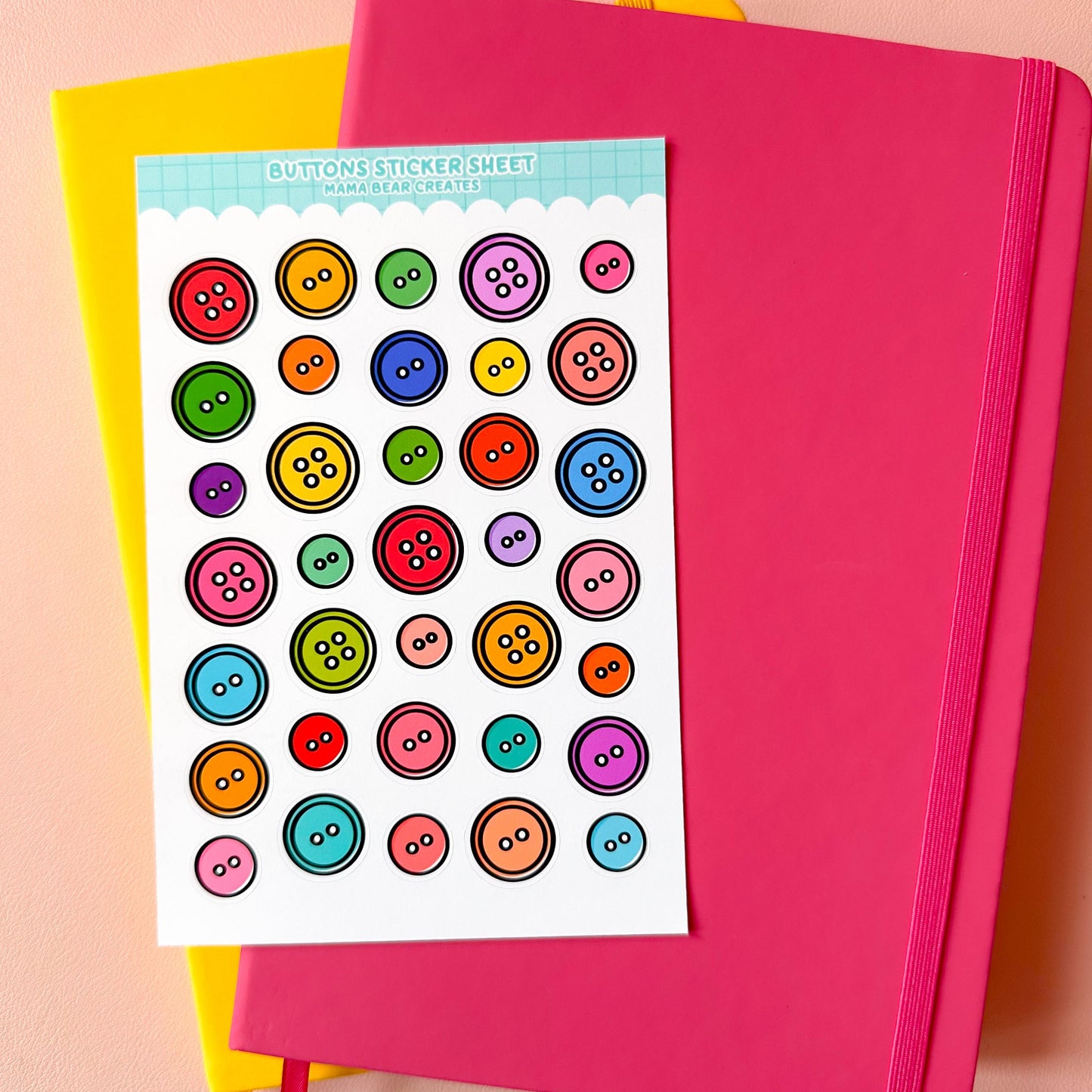 Sheet of colorful button stickers on a pink notebook with a pink background