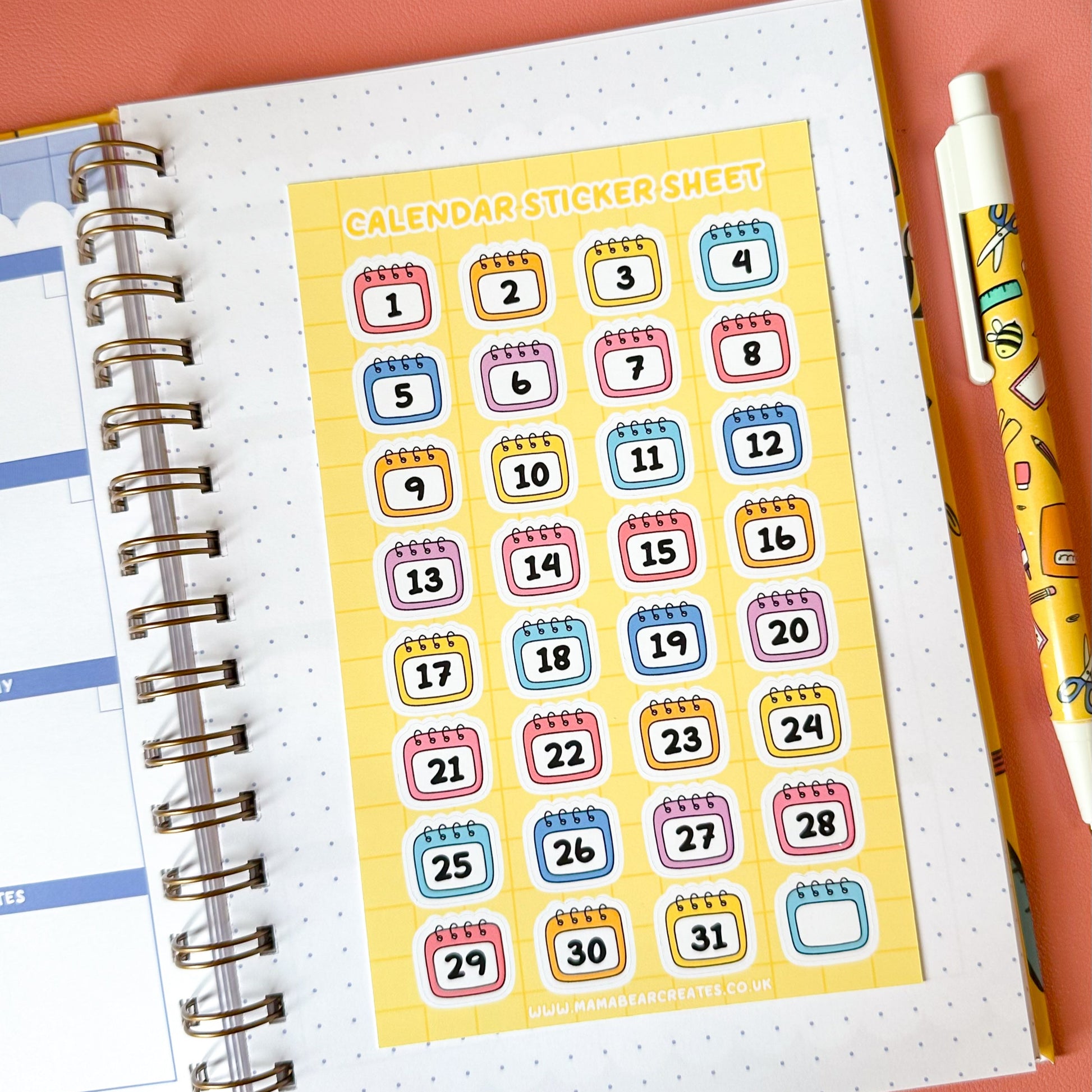 Calendar stickers sheet on a planner with a pen on a pink background