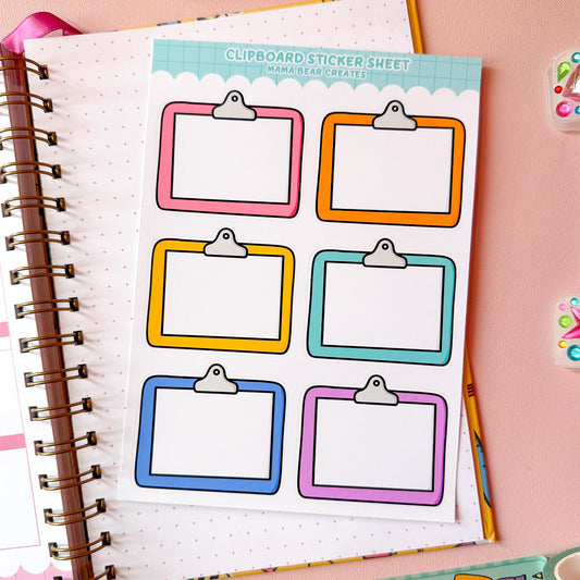 Sheet of colorful clipboard stickers on a notebook with stationery items on a pink background