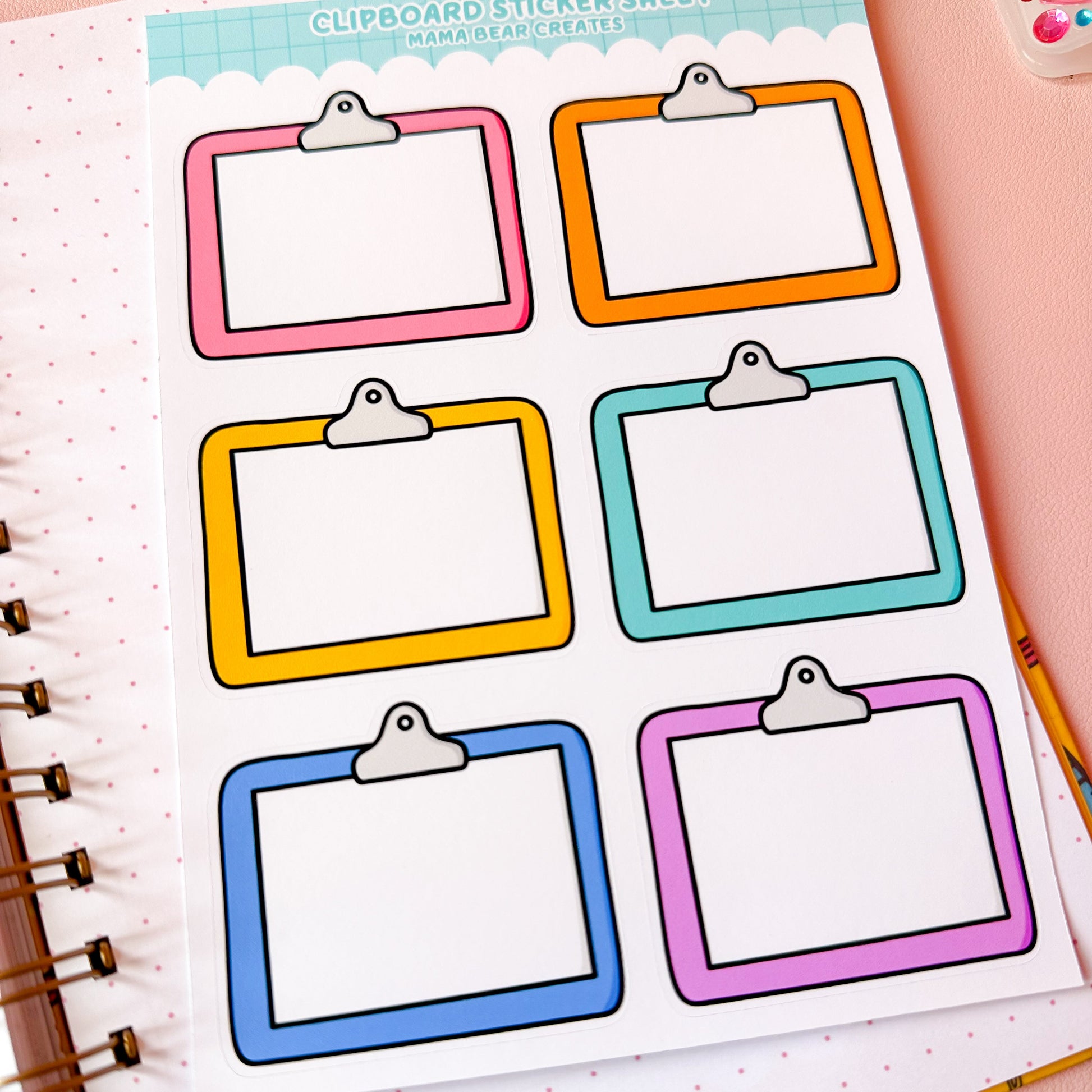 Sheet of colorful clipboard stickers on a planner page with stationery items.