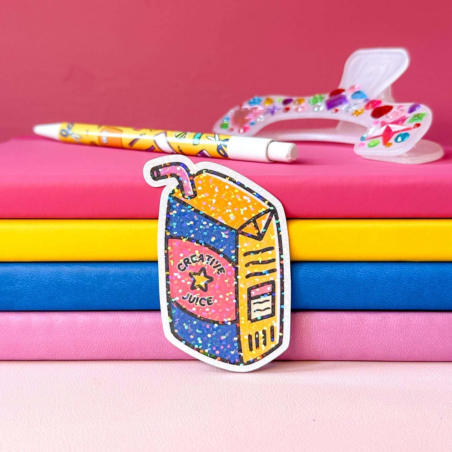 Colorful stationery items including a pen and a carton of 'Creative Juice' on a pink background.