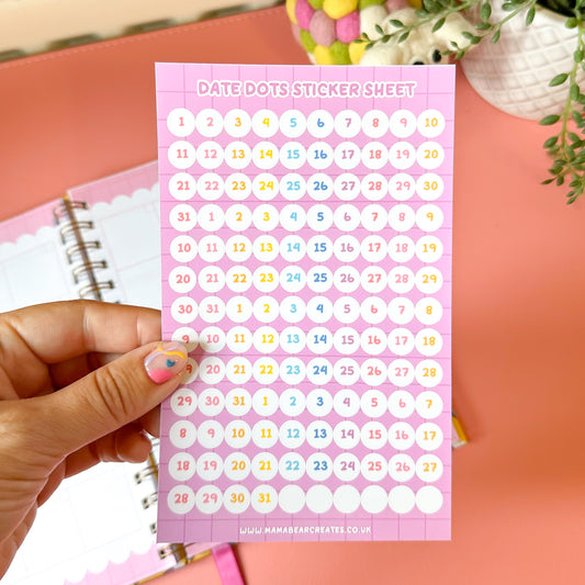 Sheet of colorful numbers held by a hand with a pink notebook in the background.