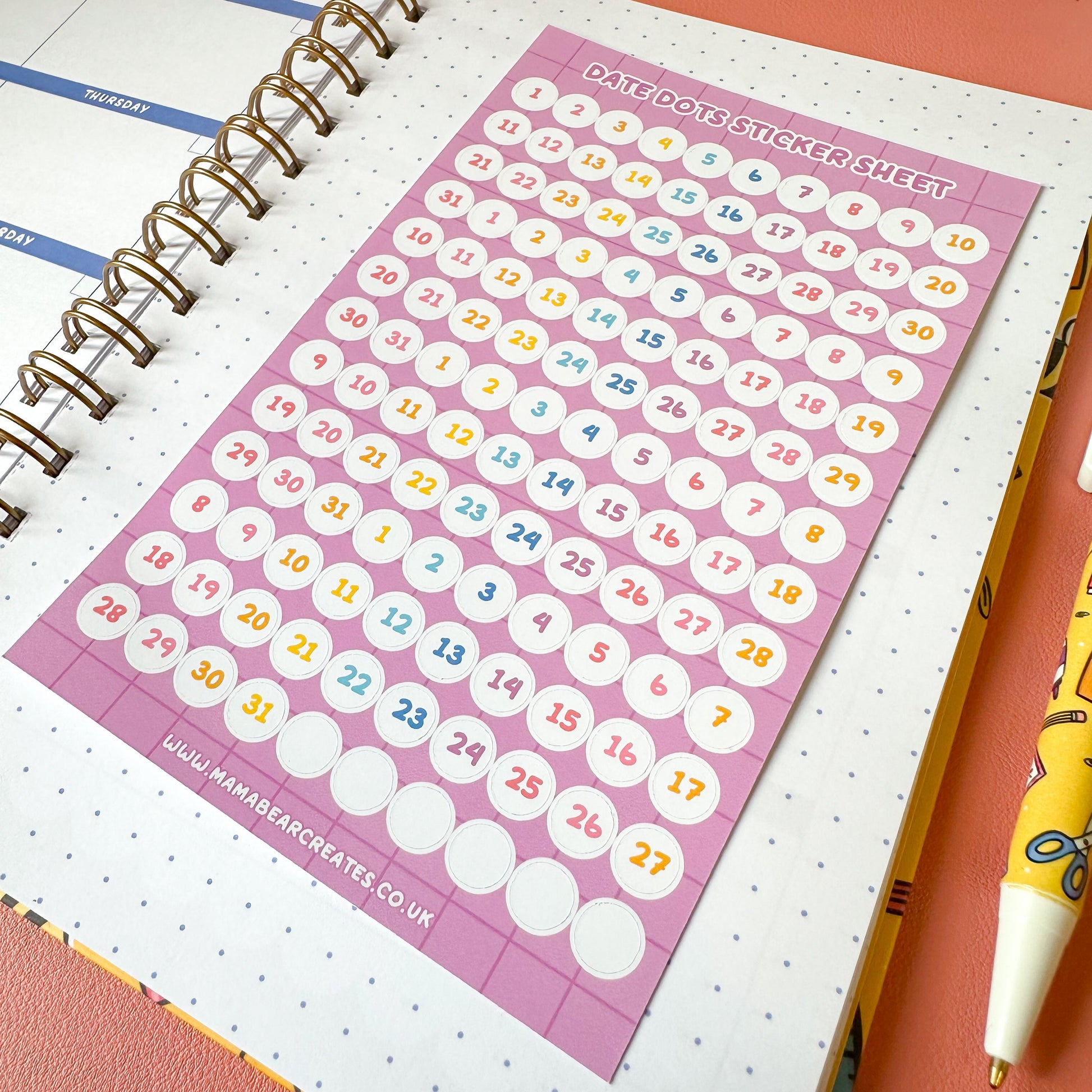 Sticker sheet with numbers on a planner with a pen next to it