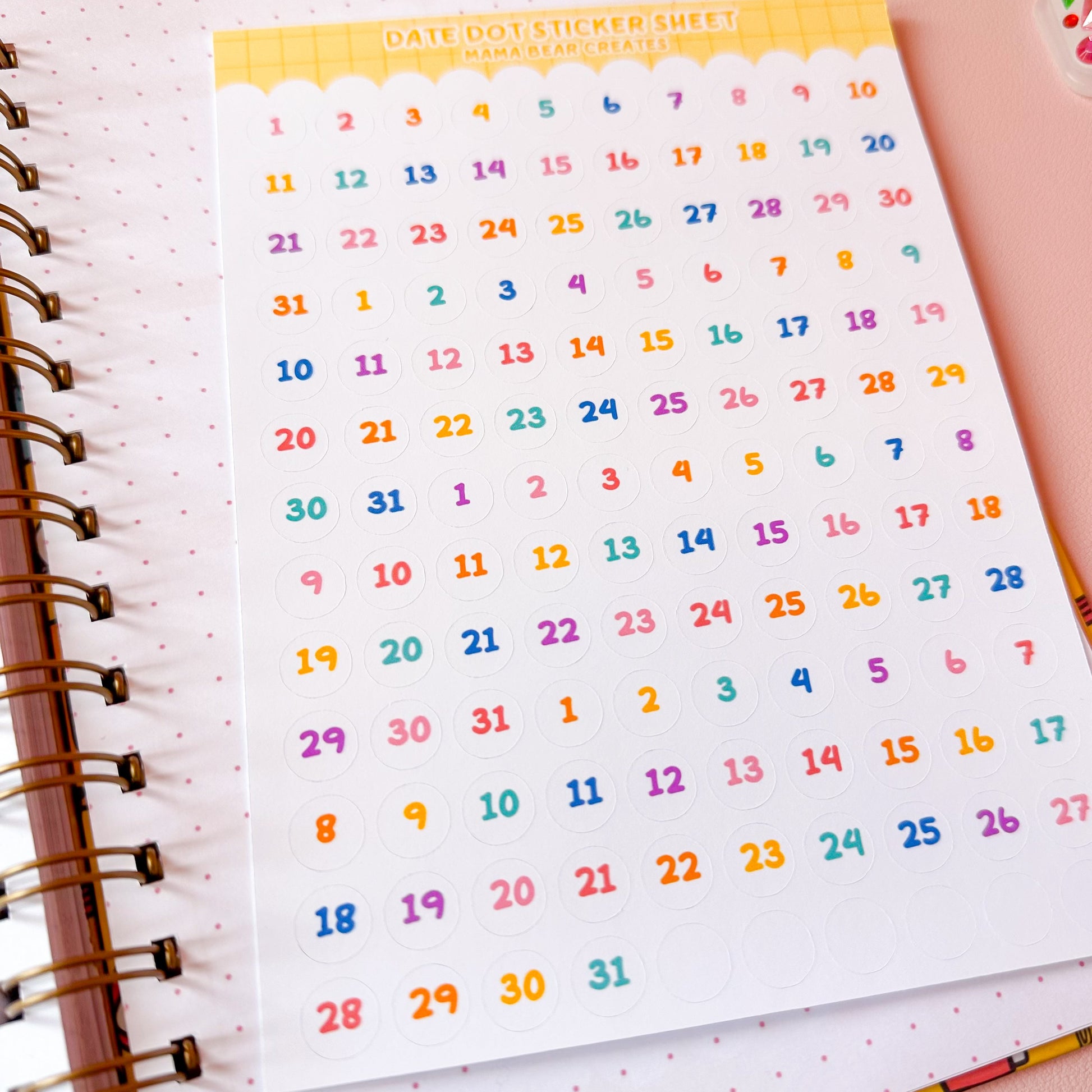Colorful calendar stickers on a planner page with a pink background