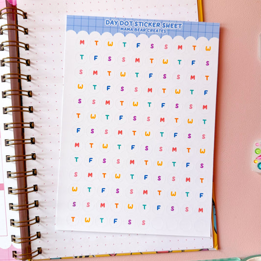 Sheet of colorful letters on a spiral-bound notebook with stationery items on a pink background