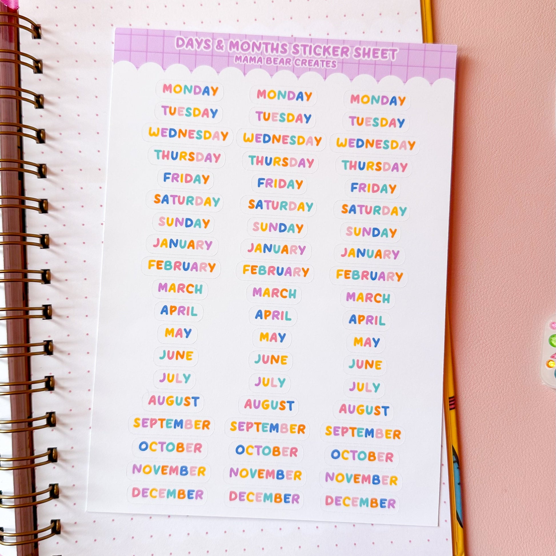Colorful calendar sticker sheet on a planner with stationery items on a pink background