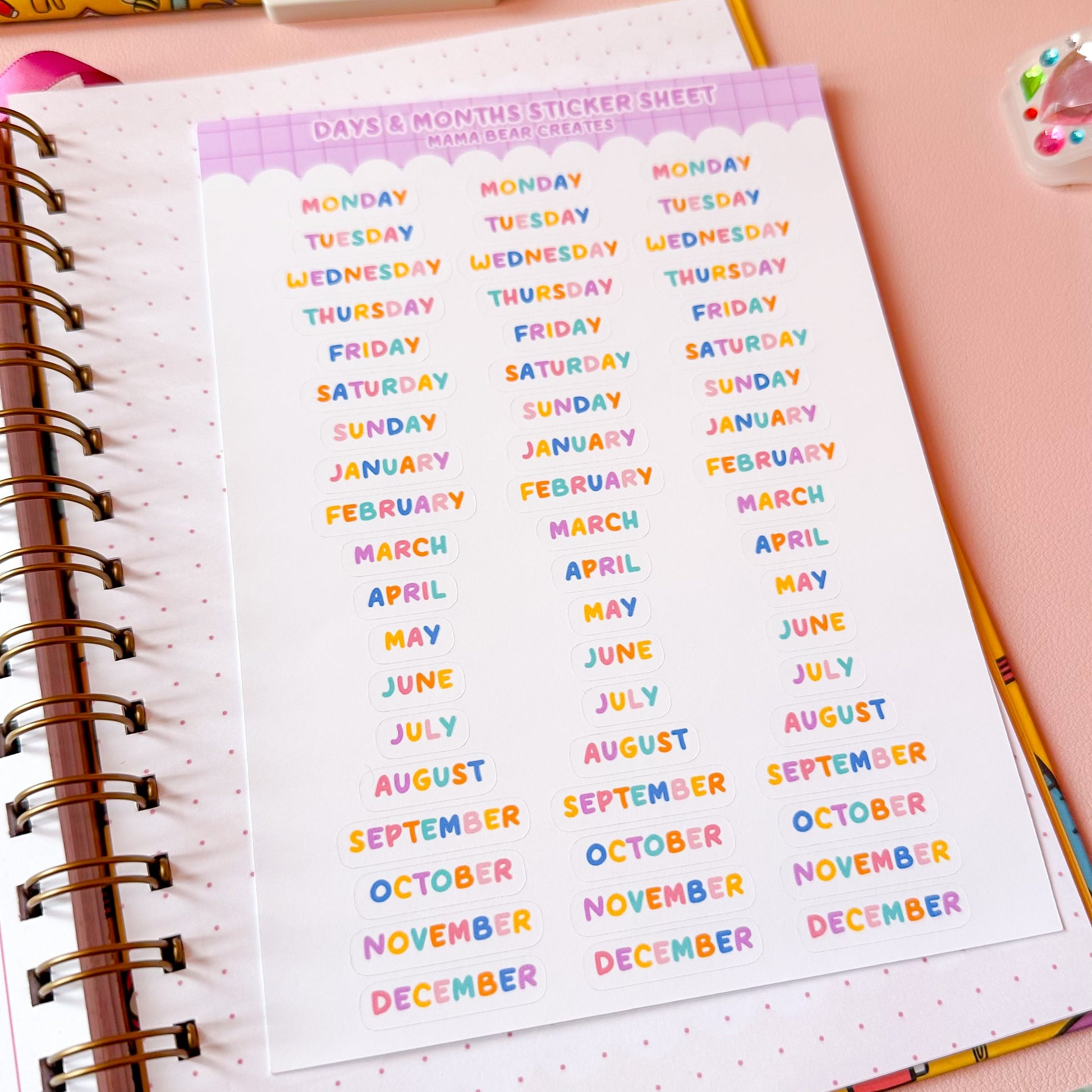 Colorful month names sticker sheet on a notebook with stationery items.
