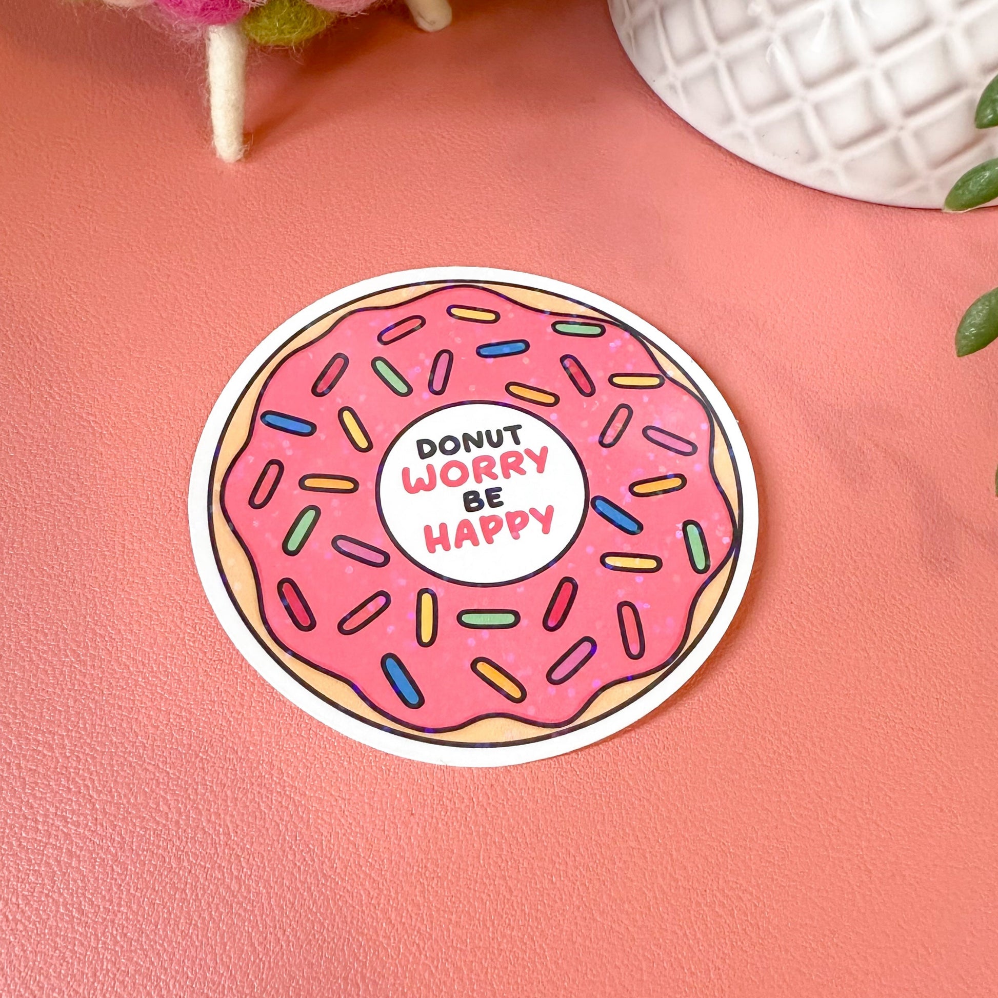 Sticker with a pink donut design and text on a pink surface