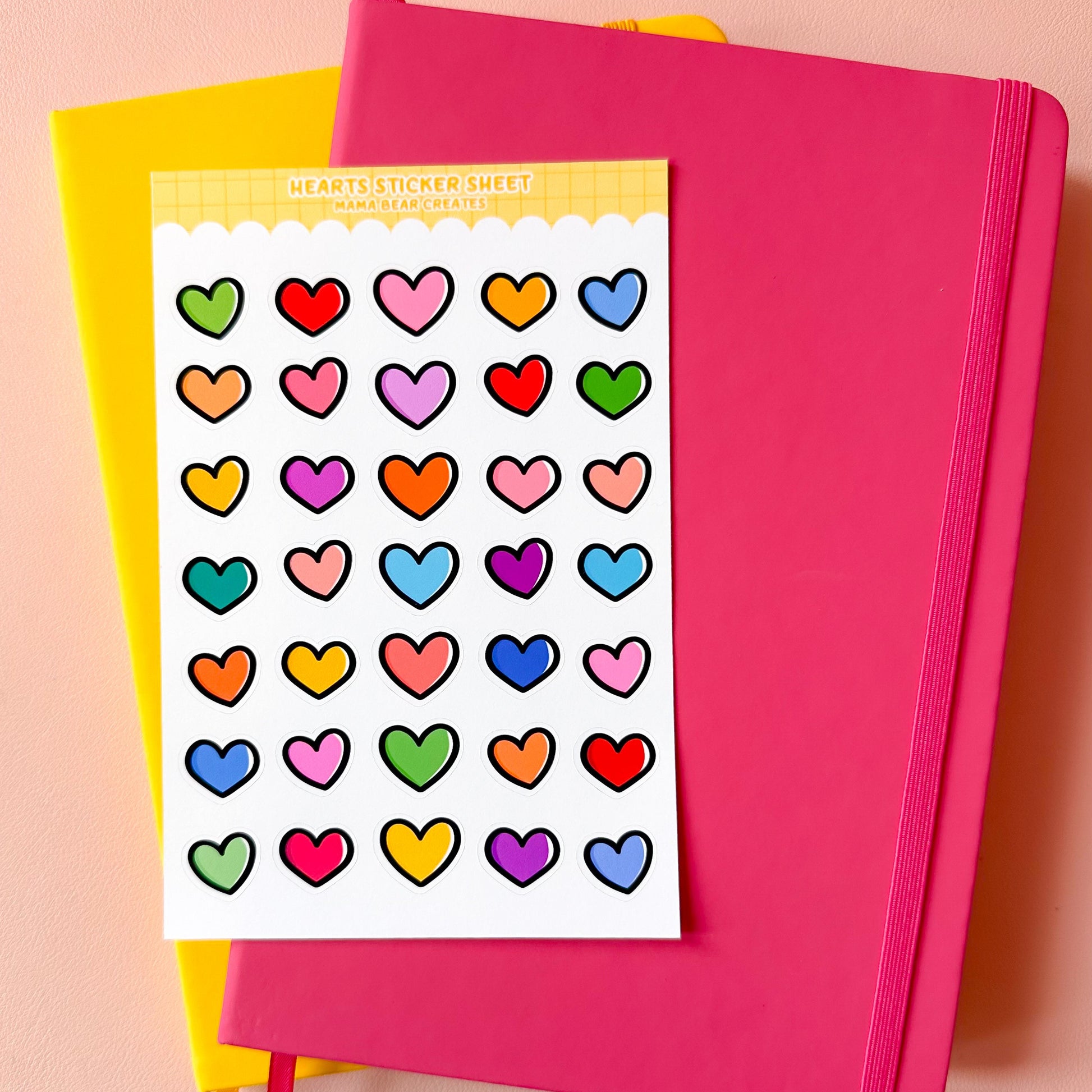Colorful heart sticker sheet on a pink notebook with a yellow cover.